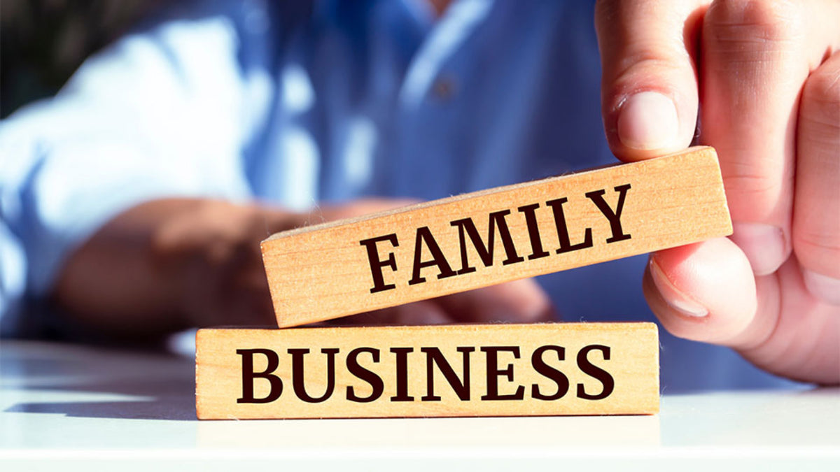 Wooden blocks with 'FAMILY' and 'BUSINESS' text held by a person.
